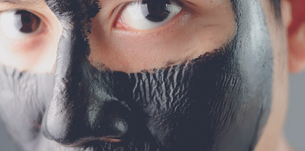 Man treating his facial skin with an activated charcoal mask