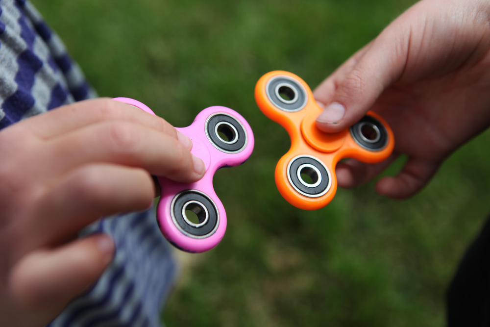 Two people holding fidget spinners